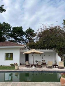 un patio con sombrilla y sillas junto a una casa en Villa avec piscine privée en Tabarka