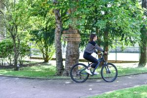 Eine Frau, die im Park Fahrrad fährt. in der Unterkunft Novotel Domaine de Maffliers - L'Isle-Adam in Maffliers