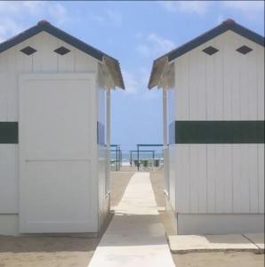 zwei weiße Gebäude mit offenen Türen am Strand in der Unterkunft Villa Il Platano con giardino Beachfront in Forte dei Marmi