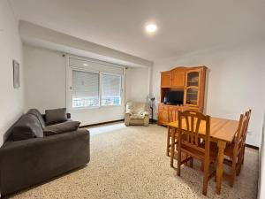een woonkamer met een bank en een eettafel bij Apartamentos playa la Perola in Roses