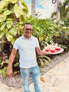 Ein Mann hält ein Tablett mit Getränken. in der Unterkunft Hotel La Tortuga in Las Terrenas