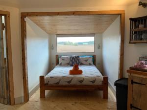 a bed in a small room with a window at Woodpecker Cabin with Hot tub in King's Lynn