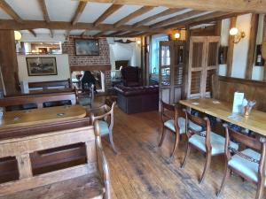 The Horse and Cart في Peasmarsh: غرفة معيشة مع طاولات وكراسي خشبية