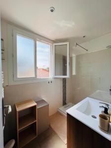 uma casa de banho com um lavatório, um WC e 2 janelas. em Villa Les Mimosas Spa-Jacuzzi em Saint-Raphaël