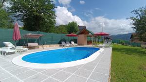 a swimming pool with chairs and umbrellas in a yard at Villa Green Oasis With Pool in Sarajevo