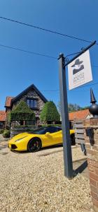 un coche amarillo estacionado frente a una casa en Boutique Bedrooms, en Thornham