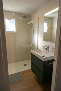 ein Bad mit einer Dusche, einem Waschbecken und einem Spiegel in der Unterkunft Apartamento Lia con piscina en Port Addaia in Port d'Addaia