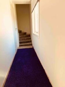 an empty hallway with a purple carpet and a window at Lovely 3-bed Flat In Stockholm in Sollentuna