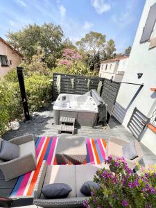 a patio with a couch and a table and a tub at Villa Les Mimosas Spa-Jacuzzi in Saint-Raphaël