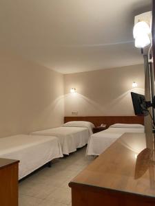 a room with three beds with white sheets at Hostal Blayet in Valencia