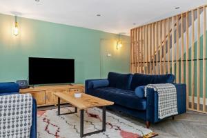 a living room with a blue couch and a tv at Teacher's Cottage in Oxwich