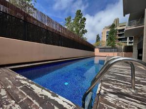 a swimming pool with a metal hand rail next to a building at Forum Playa and Pool Barcelona in Barcelona