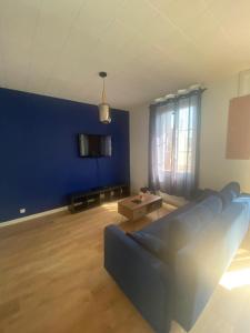 a living room with a couch and a blue wall at Le Billeron in Saint-Amand-Montrond