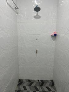 y baño con ducha de azulejos blancos y puerta de cristal. en Island Guesthouse - entire one bedroom unit with kitchen & a bathroom centrally located in Votualevu, en Nadi