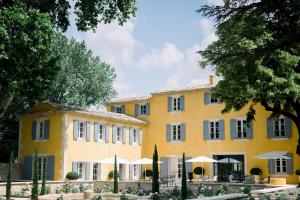 un grand bâtiment jaune avec des parapluies devant lui dans l'établissement Le Domaine du Fortin, à Ménerbes