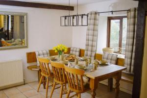 une salle à manger avec une table et des chaises en bois dans l'établissement Warren Cottage at Country Ways, à Atherington