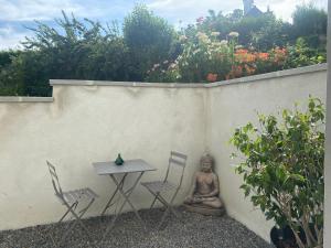 uma pequena mesa e cadeiras ao lado de uma parede em Beldi, Bel appartement dans un environnement calme em Montgermont
