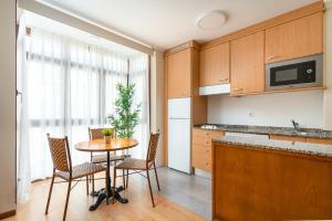 MyHouseSpain - Buen Suceso Apartments في خيخون: مطبخ مع طاولة وكراسي في مطبخ