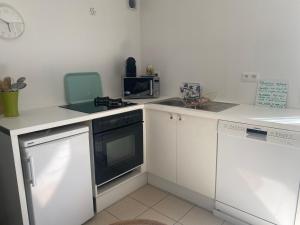 uma cozinha branca com um fogão e uma máquina de lavar louça em Beldi, Bel appartement dans un environnement calme em Montgermont