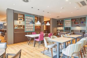 a dining room with tables and pink chairs at Premier Inn Karlsruhe City Am Wasserturm in Karlsruhe