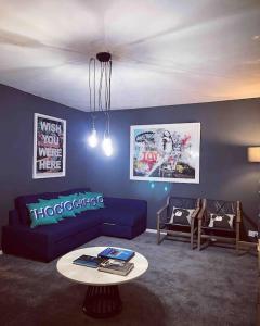 ein Wohnzimmer mit einem blauen Sofa und einem Tisch in der Unterkunft Chester/Handbridge sleeps 9 + Netflix in Hough Green