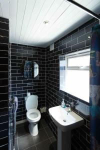 a black tiled bathroom with a toilet and a sink at Chester/Handbridge sleeps 9 + Netflix in Hough Green