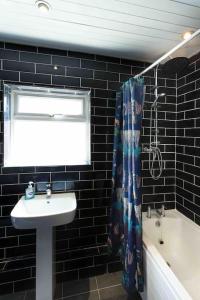 a black tiled bathroom with a sink and a window at Chester/Handbridge sleeps 9 + Netflix in Hough Green