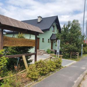 uma casa verde com um sinal em frente em Domek Dzika Orlica em Mostowice