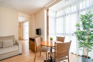 MyHouseSpain - Buen Suceso Apartments في خيخون: غرفة معيشة مع طاولة وكراسي وأريكة