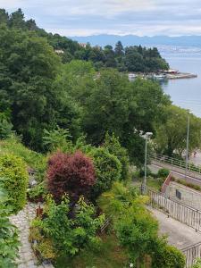 a garden with flowers and trees and a body of water at House Vali in Lovran