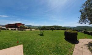 a large field of grass with a red house in the background at Hotel Tenuta dell'Argento Resort in Civitavecchia