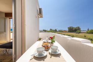 una mesa con tazas y platos de comida en el balcón en Residence Mare Azzurro by BarbarHouse, en Porto Cesareo