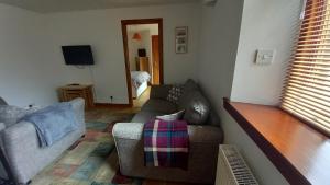 a living room with a couch and a tv at North End The Cottage in Nairn