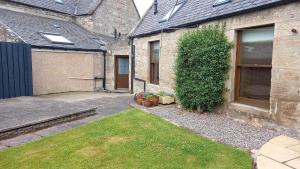 uma casa com um quintal com uma entrada e um edifício em North End The Cottage em Nairn