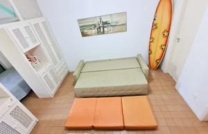 eine orangefarbene Bank in einem Zimmer mit Surfbrett in der Unterkunft Apartamento - Cond. Winbledon - Praia Toninhas in Ubatuba