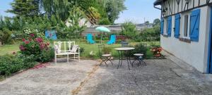a patio with chairs and a table with an umbrella at La clé des champs in Asnières +2 photos