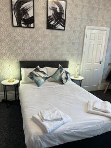 a bedroom with a white bed with two towels on it at OYO Marine Parade Hotel, Eastbourne Pier in Eastbourne