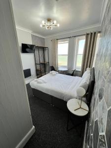イーストボーンにあるOYO Marine Parade Hotel, Eastbourne Pierのベッド、テーブル、椅子が備わるホテルルームです。