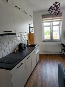 a kitchen with white cabinets and a black counter top at Blues Rooms in Gdynia +46 photos