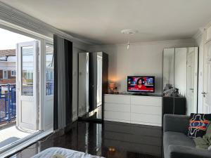 a living room with a tv and a couch at Large room with balcony overlooking London in London