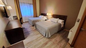 una camera d'albergo con due letti e una finestra di Hotel Diego de Almagro Coyhaique a Coihaique