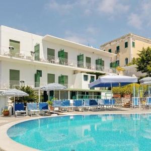una piscina frente a un hotel con sillas y sombrillas en Casa della Frutta en Anacapri