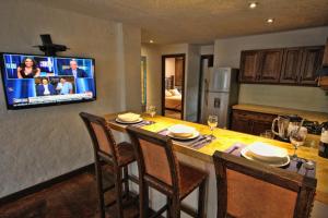 a kitchen with a table with chairs and a television on the wall at Casa Del Reloj in Medellín
