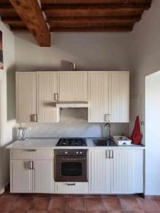 a kitchen with white cabinets and a stove top oven at Le petit refuge in Capraia