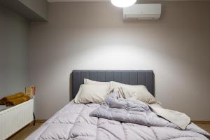 Bright 2BDR Apartment Downtown Exarcheia! في أثينا: سرير غير مرتب وعليه بطانية في غرفة النوم