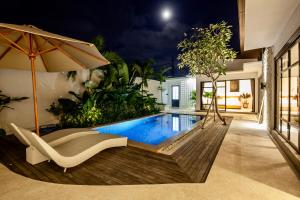 a swimming pool with a chair and an umbrella at Billi Bali Villa in Canggu