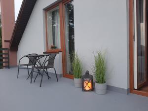 a patio with a table and chairs and a lantern at Pokoje gościnne OSKAR in Łeba