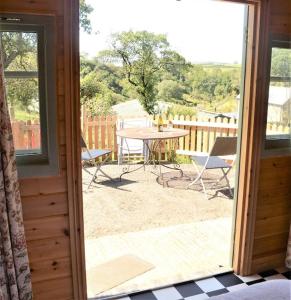 an open door to a patio with a table and chairs at Woolcombe Cabin in East Allington