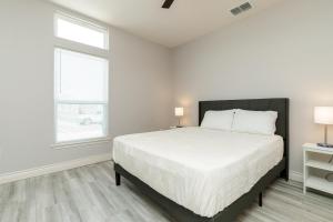 a white bedroom with a large bed and two windows at Luxurious 4-Bedroom Retreat Near the Beach: King Suite, High-Speed WiFi, Free Parking in Corpus Christi