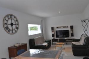 uma sala de estar com um grande relógio na parede em Villa An Castine avec spa pour 6pers proche plages em Saint-Cast-le-Guildo